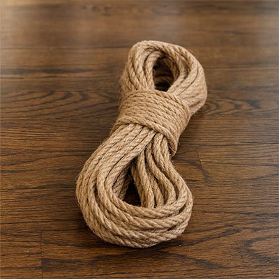 Corde en sisal naturelle pour arbre à chat enroulée et posée sur un sol en bois
