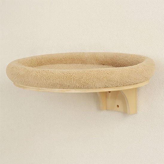 Plateforme murale ronde pour chat avec coussin moelleux fixée sur un mur clair
